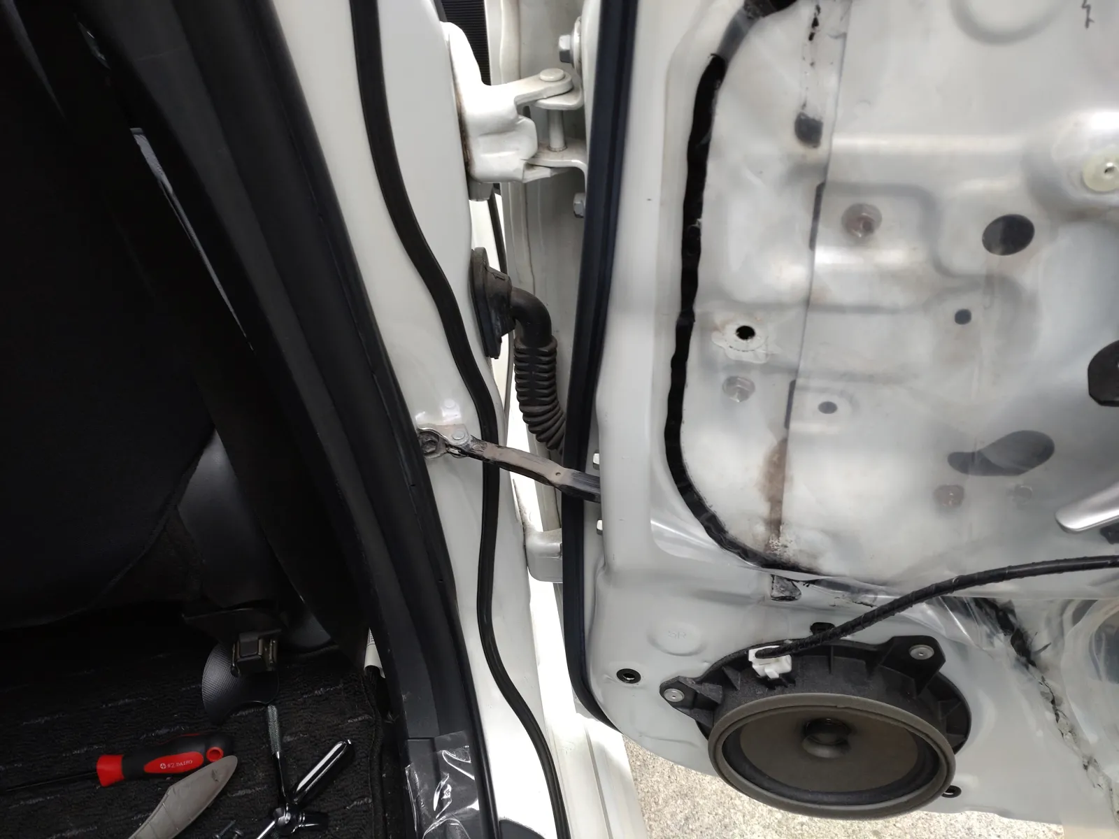 目的の部品はドアをつなぐ黒い棒

車体側の１つ、ドア側の２つのボルトを外すと取れます。
ネジを外したら、ドアのサービスホールから古い部品を外せます。

交換後はドアを閉める直前に少し抵抗が生まれるので、”バン”と安っぽい閉まる音が緩和されて、ジェントルな閉まり音に変わります。
デッドニングで開閉音を改善しようと思っていましたが、ありがたい副作用です