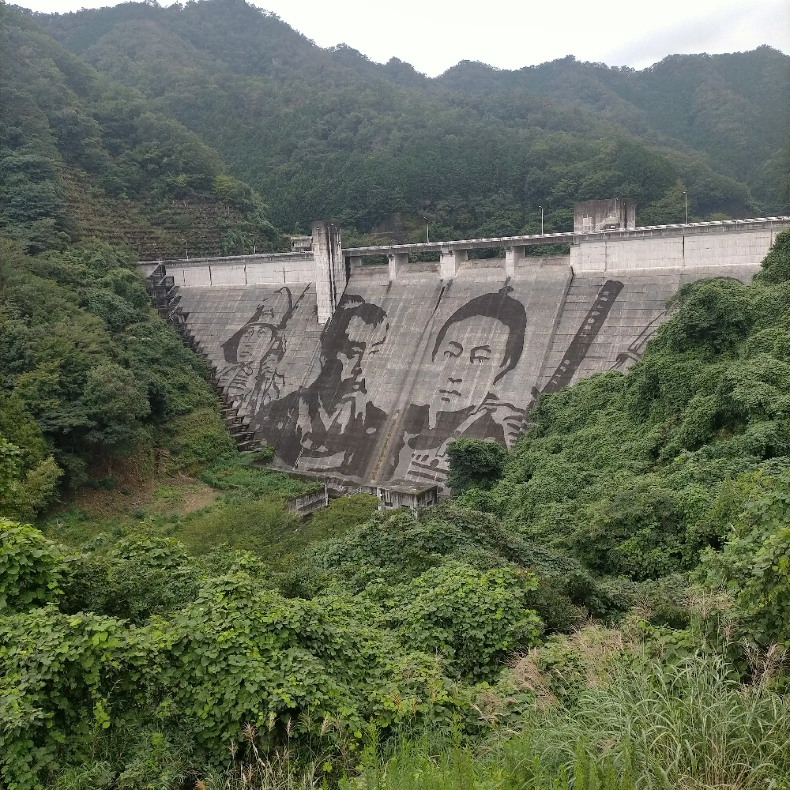 足利市にある松田川ダム30周年記念のダムアート。ケルヒャーの高圧洗浄機で、汚れを水で落として描いているそうです。ダムとの自撮り写真を見せて記念ダムカードを頂きました。